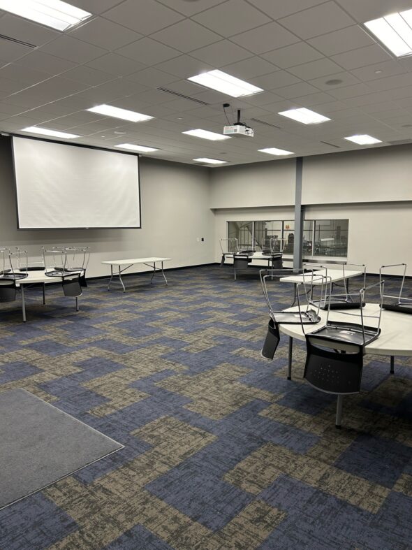 Kirkwood Bank & Trust Meeting Room C with tables and chairs spread throughout the room and a projector screen hanging down from the ceiling